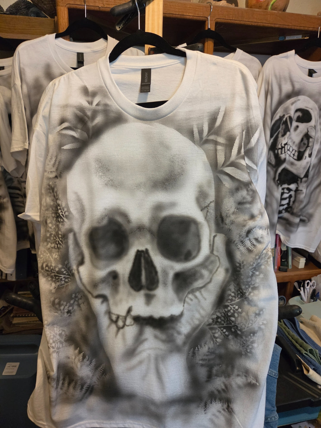 Hand-airbrushed black and white skull framed by a fern and botanical wreath on a white XL Gildan t-shirt, goth botanical one-of-a-kind