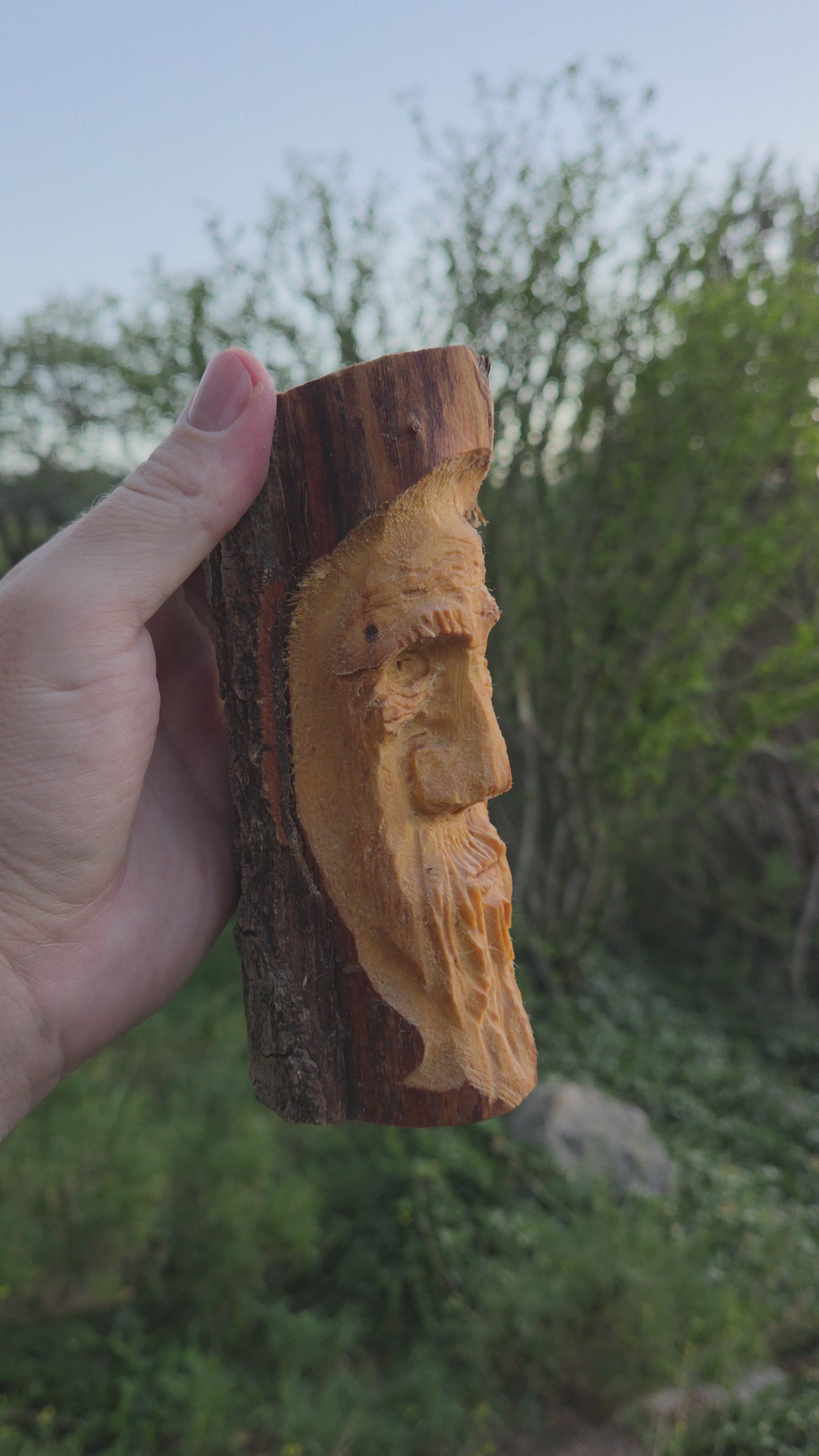 Turning video of a hand-carved cottonwood wood spirit face carving held in hand outdoors in High Rolls, New Mexico