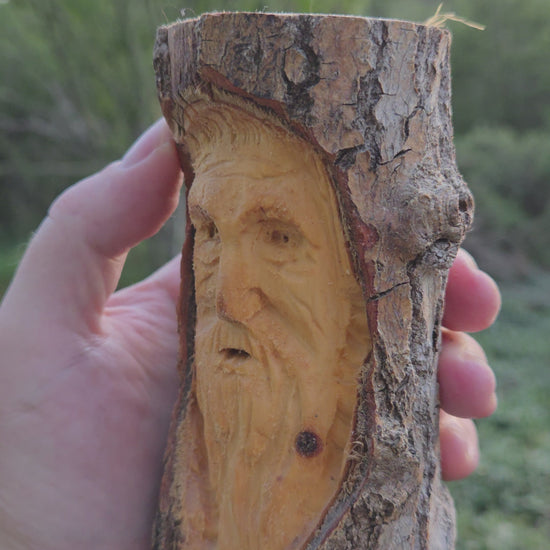 Turning video of a hand-carved cottonwood wood spirit face carving held in hand outdoors in High Rolls, New Mexico