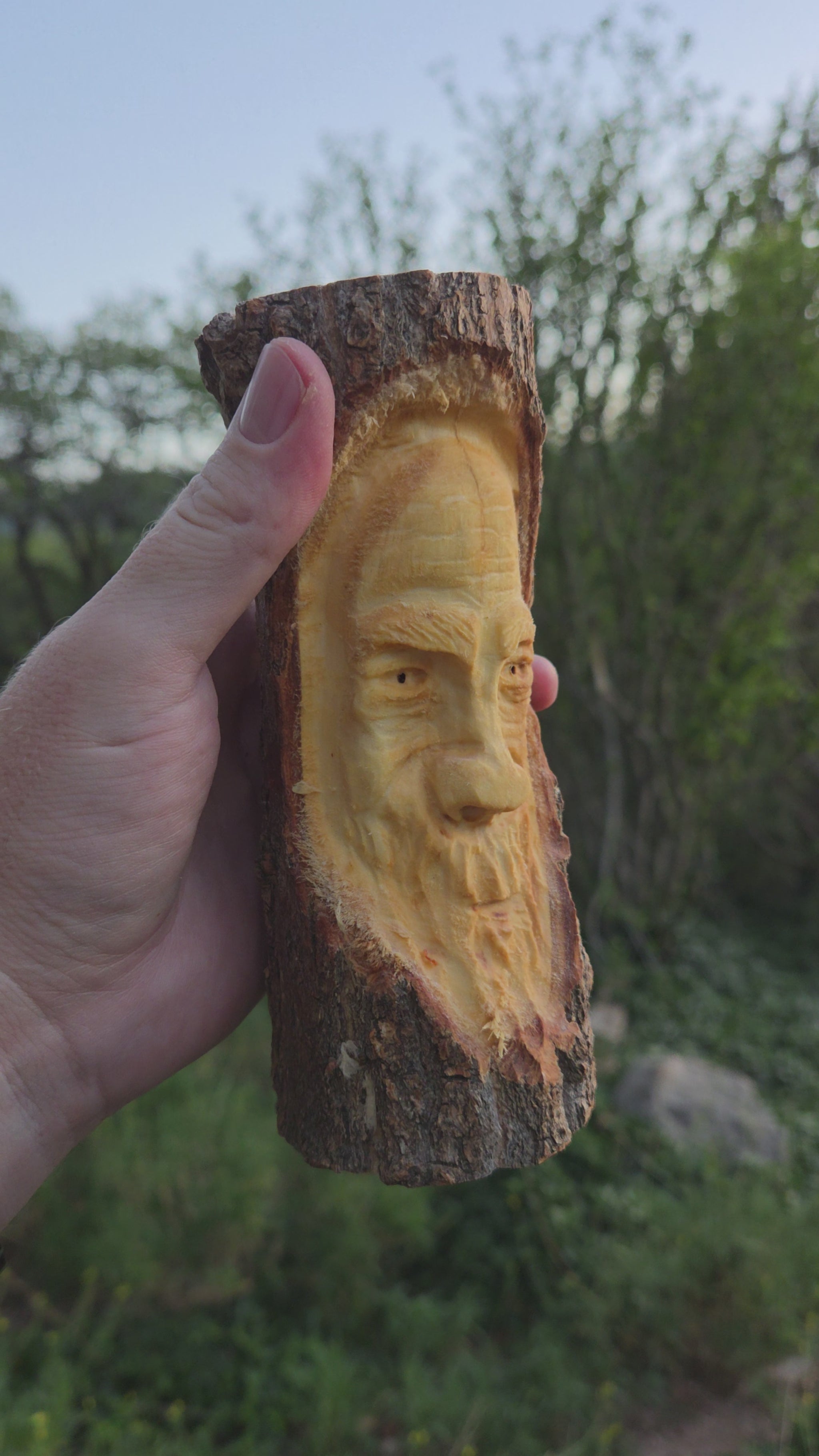 Turning video of a hand-carved cottonwood wood spirit face carving held in hand outdoors in High Rolls, New Mexico