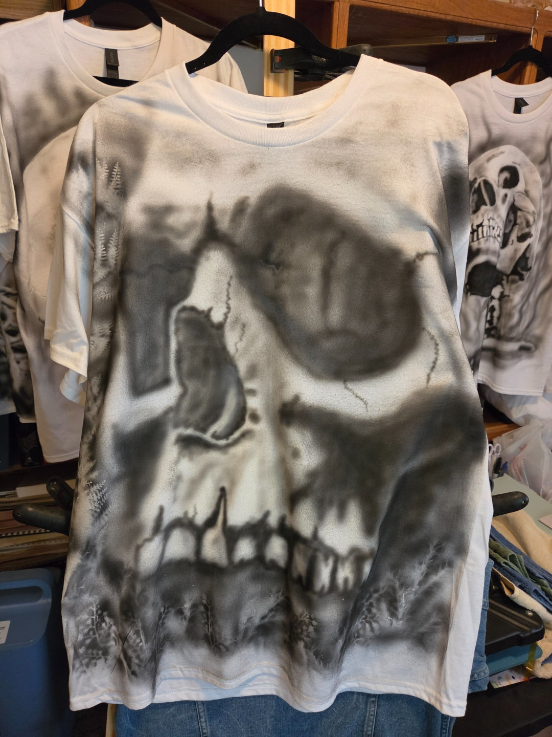 Oversized hand-airbrushed black and white skull covering a white XL Gildan t-shirt with fern silhouettes, grunge horror streetwear one-of-a-kind