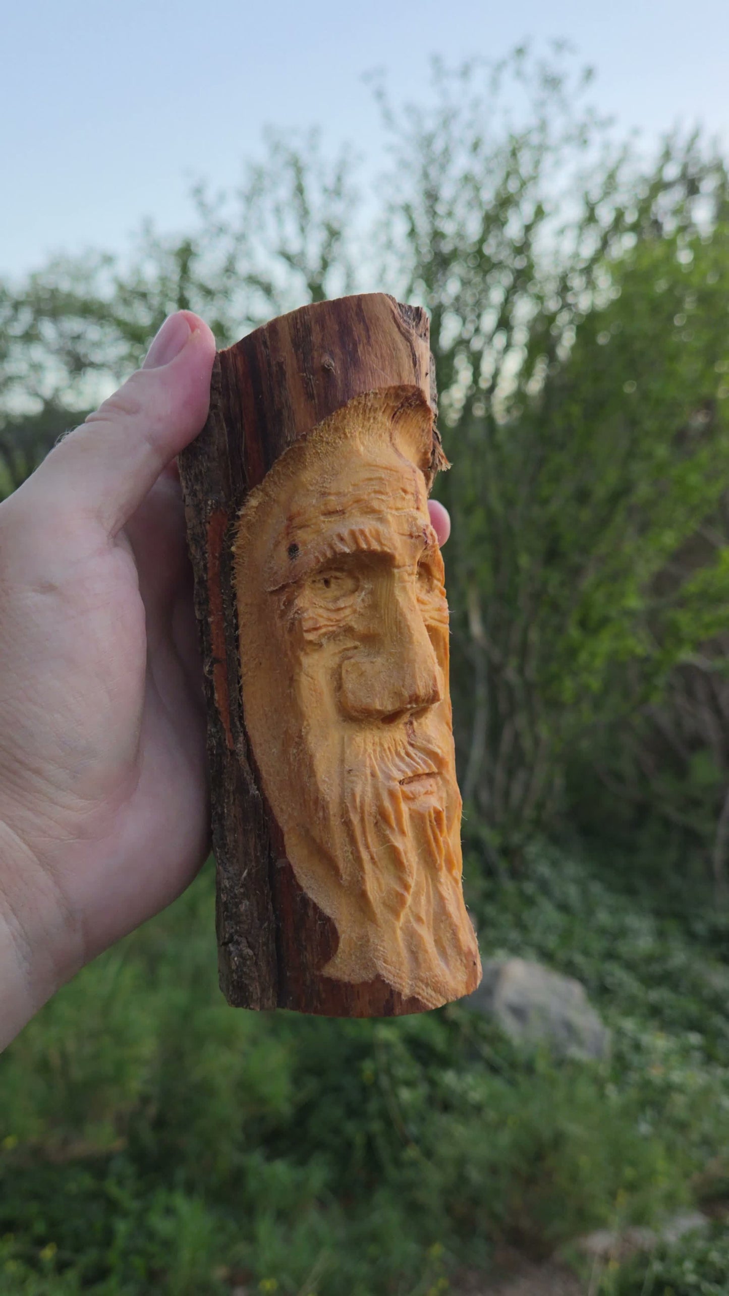 Hand-carved cottonwood wood spirit on a live-edge slab with hawk nose and long flowing beard, held in hand in New Mexico