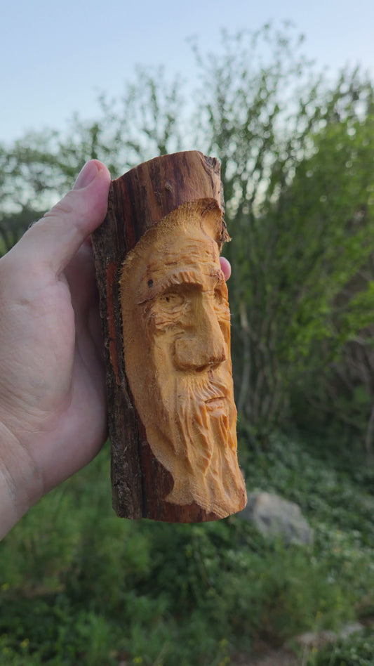 Hand-carved cottonwood wood spirit on a live-edge slab with hawk nose and long flowing beard, held in hand in New Mexico